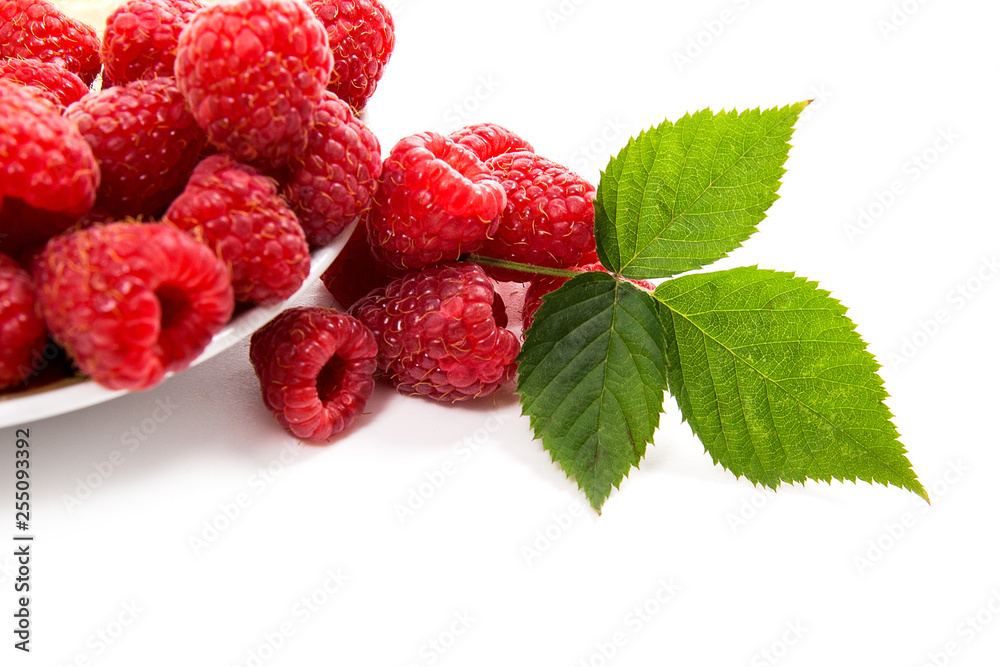 Small plate with ripe raspberries and green leaf isolated on white background. Small plate with ripe raspberries and green leaf isolated on white background.