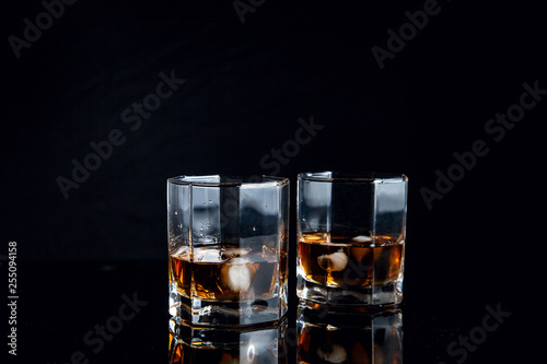 Two glasses of whiskey with ice isolated on black background..