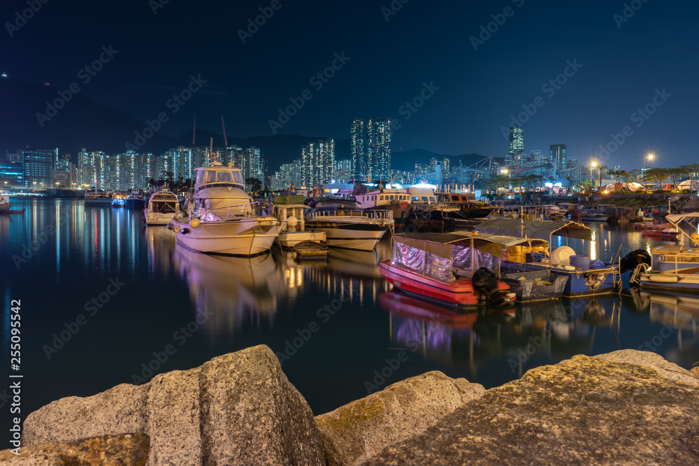 Night scene of Fishing village a small community with fishing boats and night cityscape at Lei Yue Mun water bay, Hong Kong.