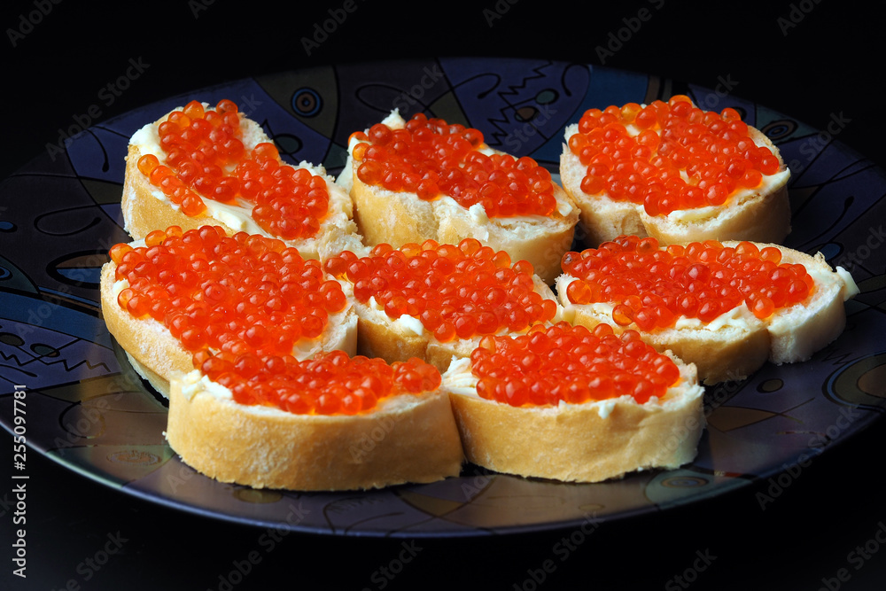 Red caviar on sandwiches and lemon on a black background Red caviar on sandwiches and lemon on a black background