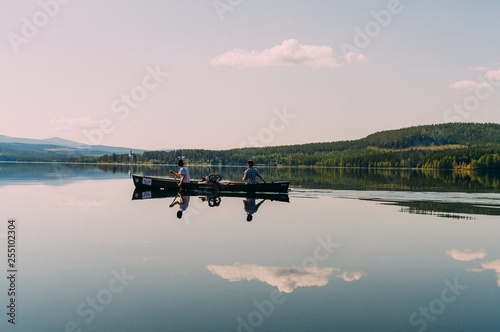 Zwei Paddler im Kanu auf spiegelglattem See in Schweden