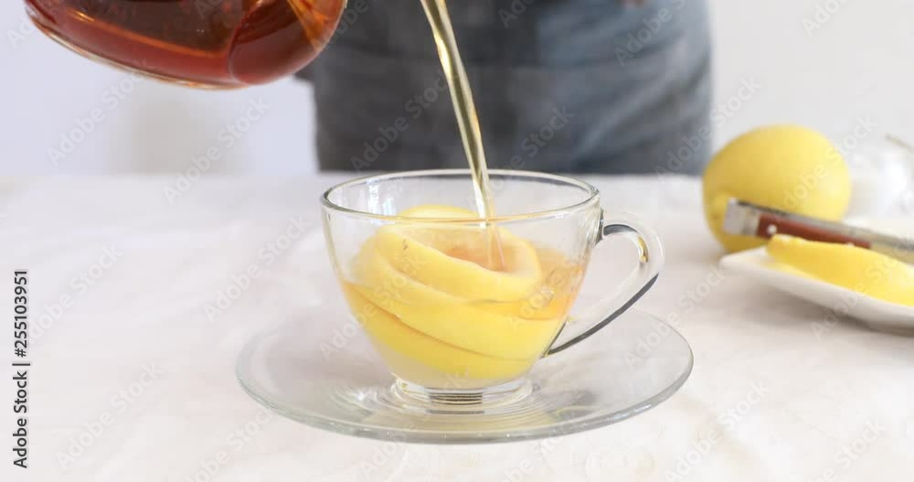 Pouring water into glass cup with lemon slices to make lemon black tea
