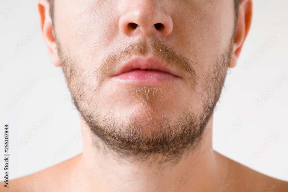 Obraz premium Young adult man with short beard. Isolated on gray background. Men's issues. Face close up. Front view.