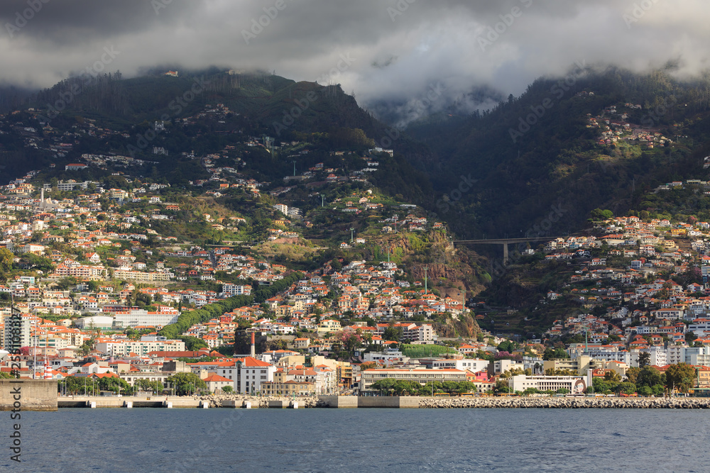 Beautiful cityscape view of the city Funchal, Madeira, seen from the Atlantic ocean, with ominous clouds