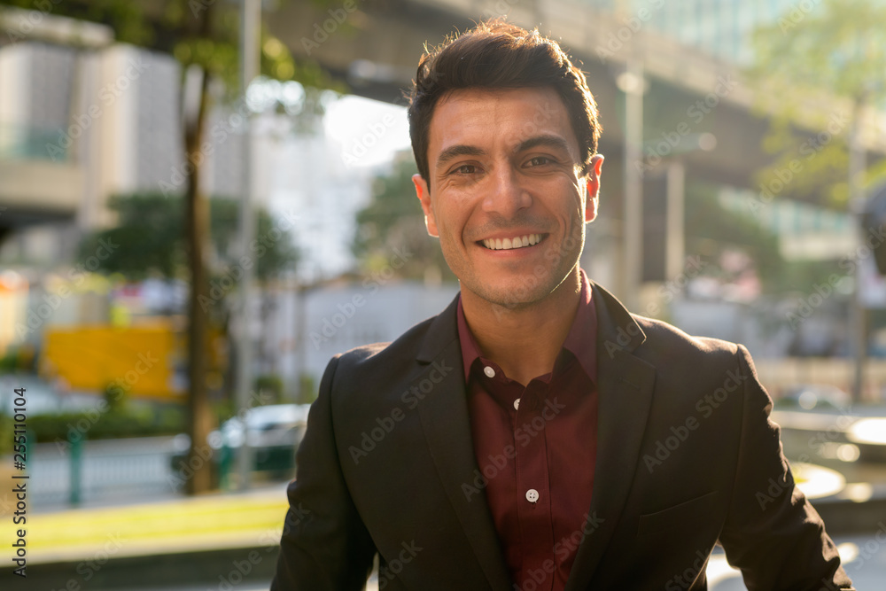 Face of happy young handsome Hispanic businessman smiling outdoors Face of happy young handsome Hispanic businessman smiling outdoors