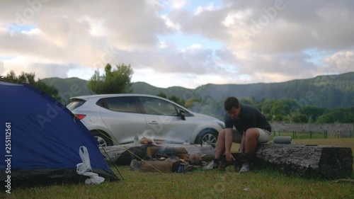 camping in nature with a fire and a guy playing with a dog on the background of a landscape and car