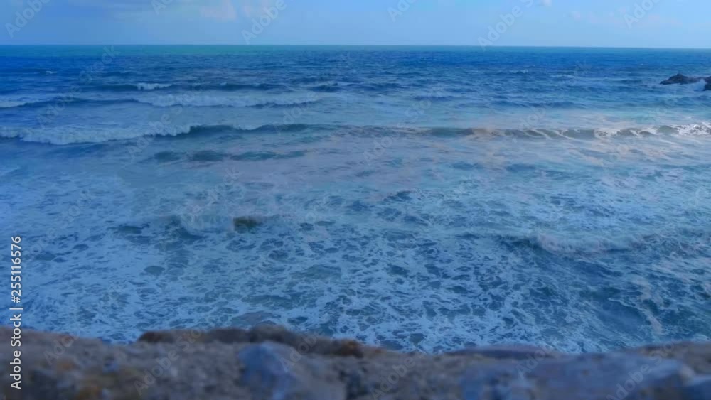 Stormy sea with big blue waves with foam whitecaps and splashes. Large waves in a windy turbulent ocean Stormy sea with big blue waves with foam whitecaps and splashes. Large waves in a windy turbulent ocean