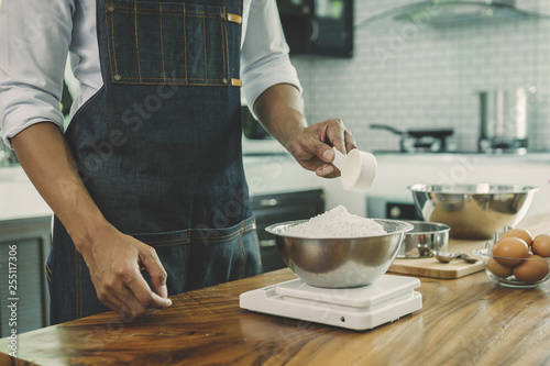 Men are sifting flour to make bakery; happy family in kitchen