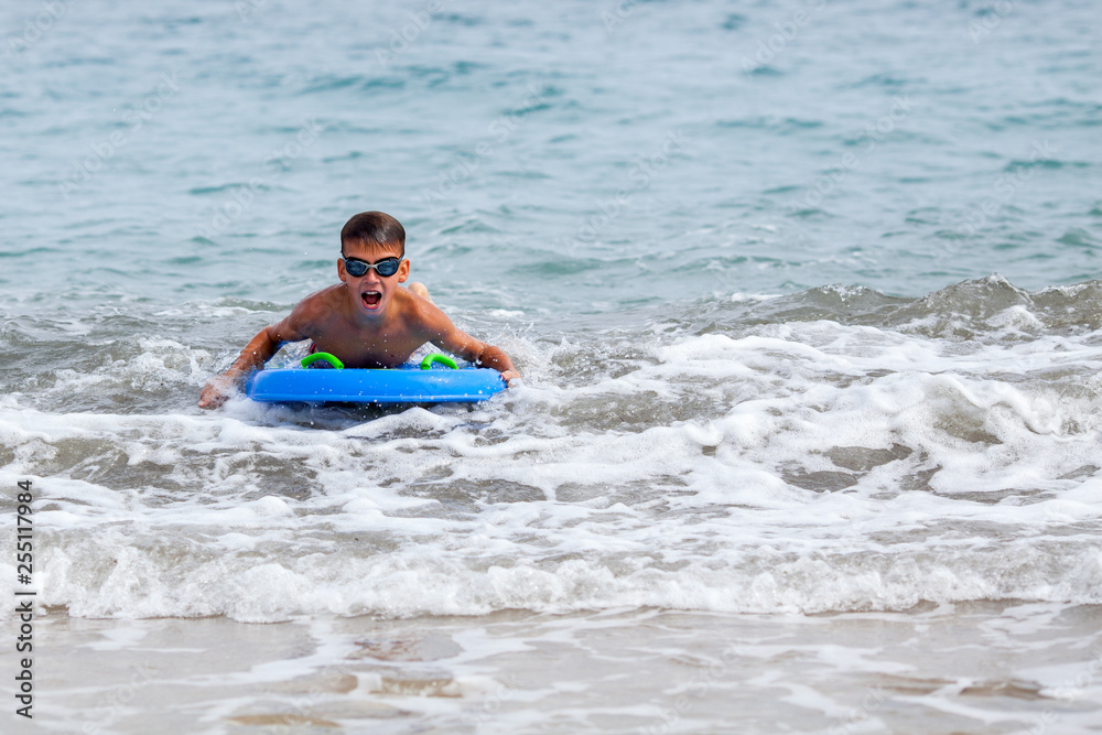 Portrait of happy cute boy swimming in sea, surf board, outdoor