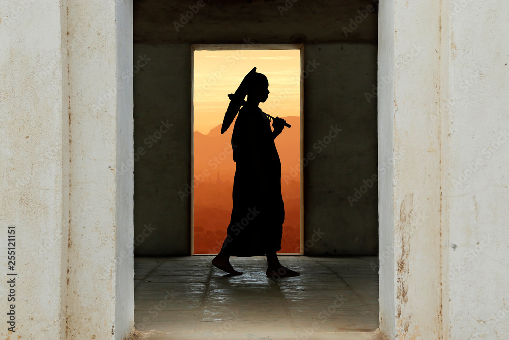 silhouette of monk with umbrella walking in temple