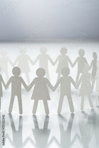 Bild auf Leinwand Circle of paper people holding hands on white surface