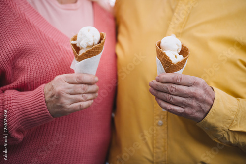 cropped view of senior couple holding ice cream cones