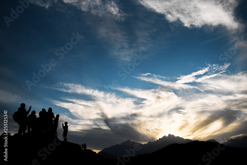 beautiful sunset in the mountains with the outlines of people on top of the sky in the clouds