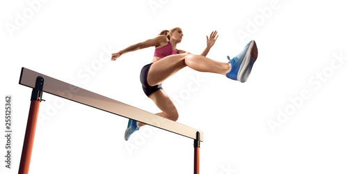 Isolated Female Track and field athlete jumps over the barrier on white background photo