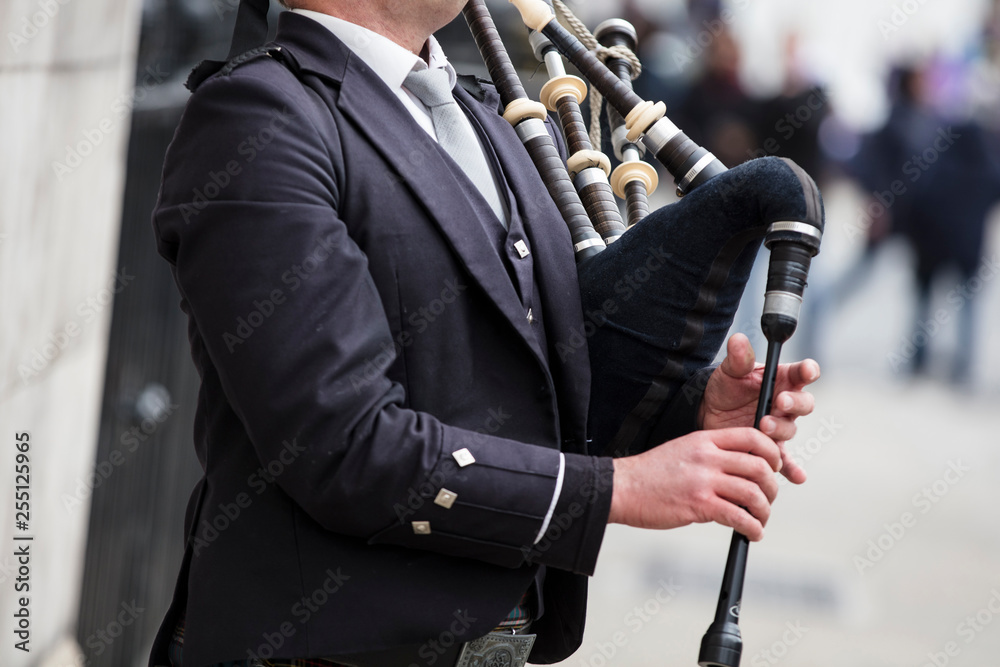 Scottish bagpiper dressed in traditional dress performing on the street