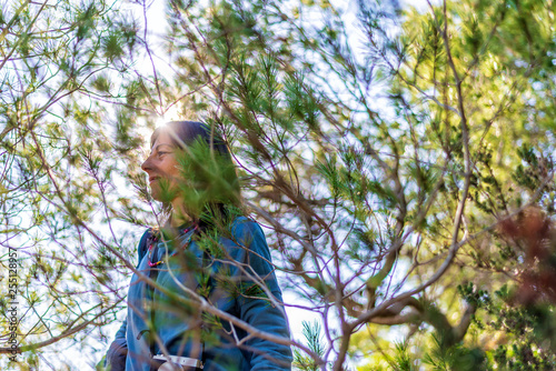 Side view of a young woman wearing casual clothes walking though the vegetation in a bright day