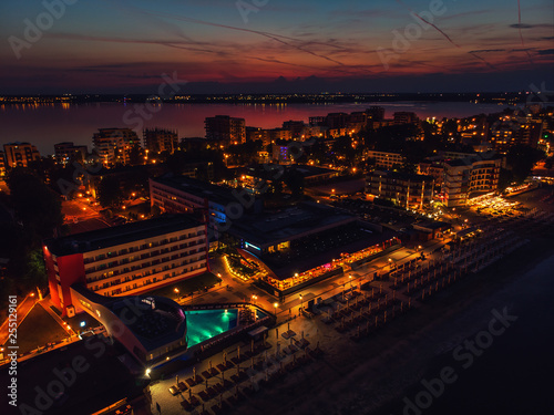 Drone bird's eye view photo of famous resort of Mamaia as seen at night with dazzling lights and waves