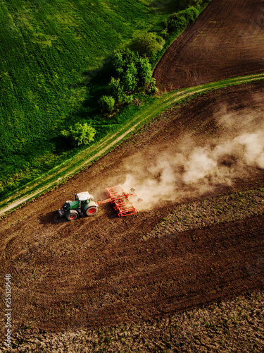 Tractor cultivating field, kicking up rocks and dust in early morning photo