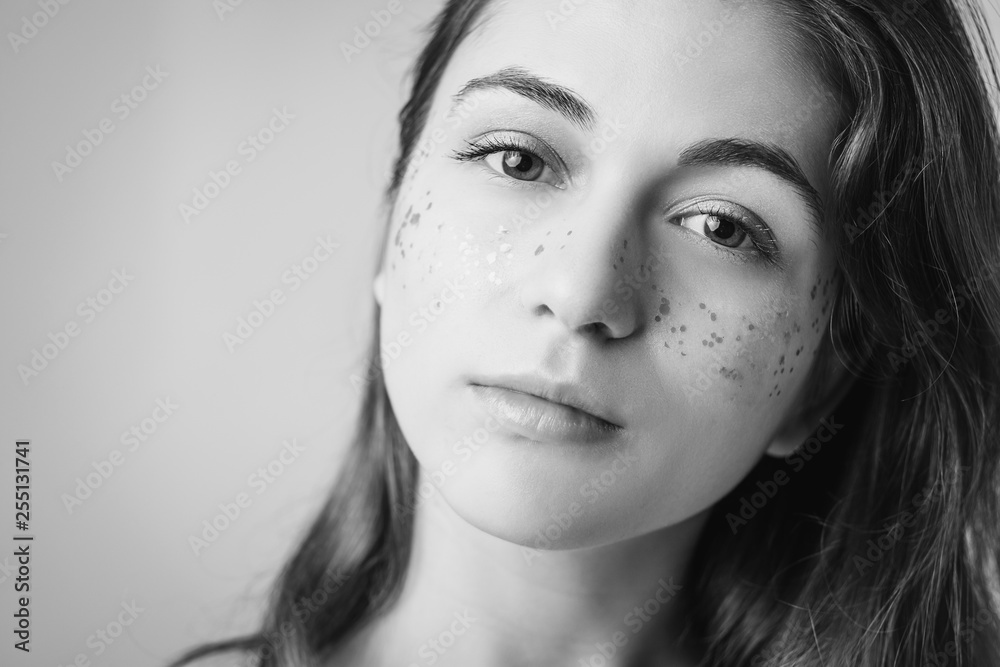 Fototapeta premium Young female portrait. Natural woman beauty. Fashion glitter freckles makeup. Copy space for text. Black and white.