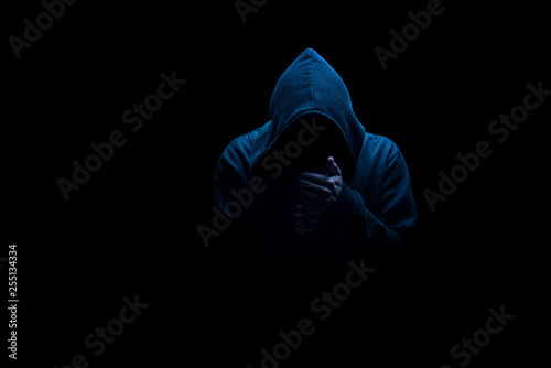 Man in black hood in the night darkness, dimly lit, concepts of danger, crime, terror photo