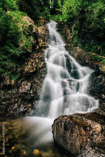 Mountain waterfall on the rocks covered with moss in the forest