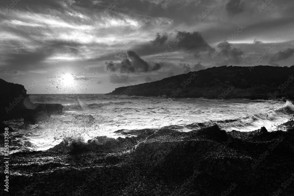 white-black picture of sunset over the sea, with big and strong waves. 