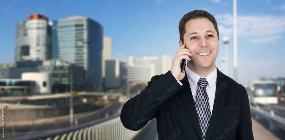 Businessman Talking On The Phone With Business City and Corporate Buildings In Background Businessman Talking On The Phone With Business City and Corporate Buildings In Background