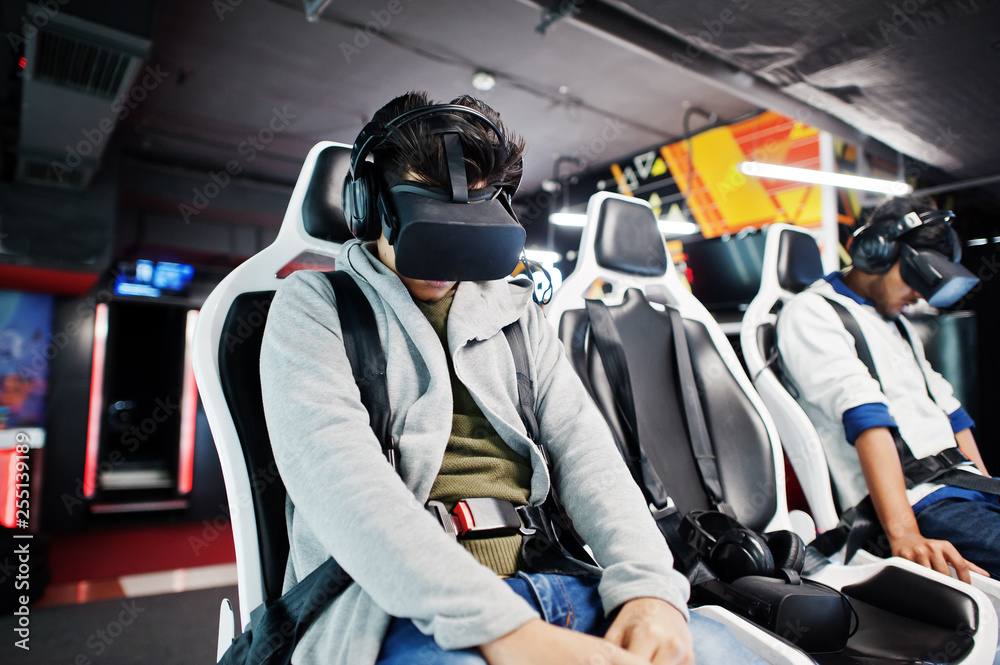 Two young indian people having fun with a new technology of a vr headset at virtual reality simulator. Two young indian people having fun with a new technology of a vr headset at virtual reality simulator.