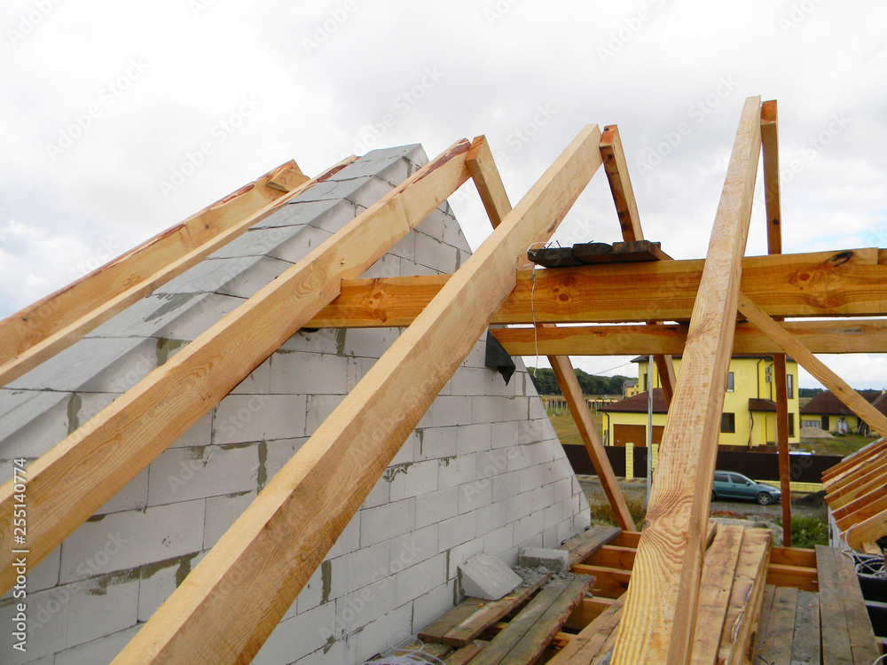 House roof top wooden frame construction. Unfinished house roofing construction wooden beams, trusses, timber.