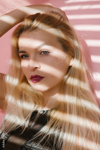 Young blonde woman portrait. Female fashion model. Blinds shadow effect.