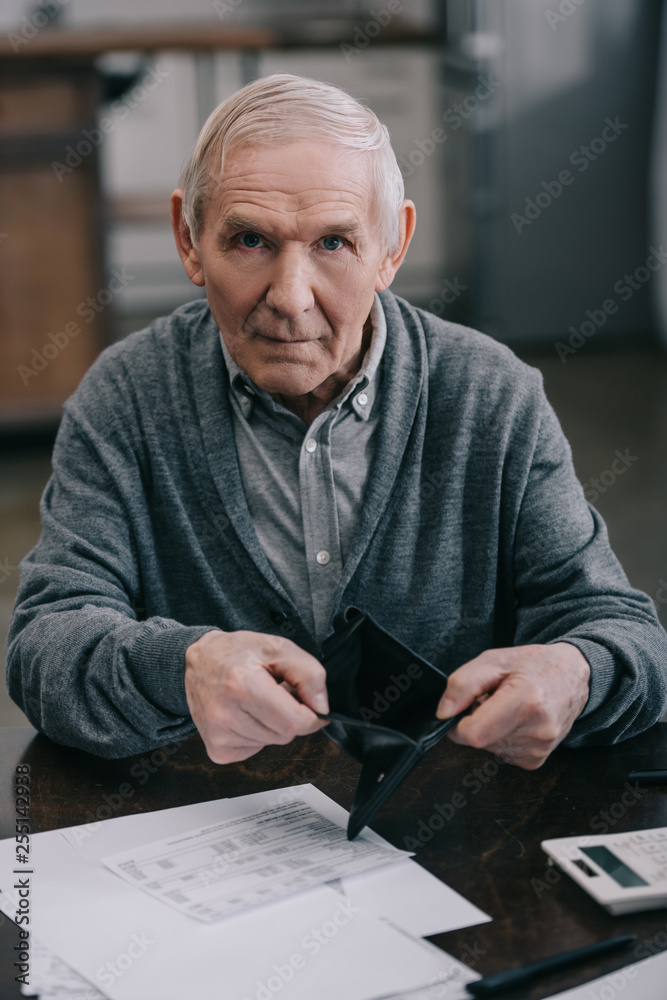 senior man holding empty wallet and looking at camera senior man holding empty wallet and looking at camera