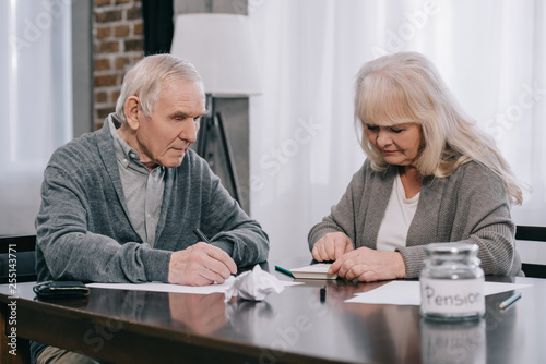 senior couple sitting at table with paperwork and using calculator