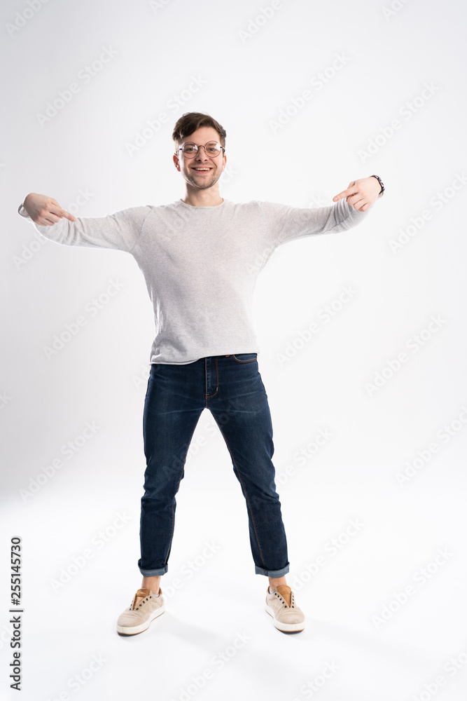 Handsome man wearing glasses amazed and smiling to the camera while presenting with hand isolated on white.