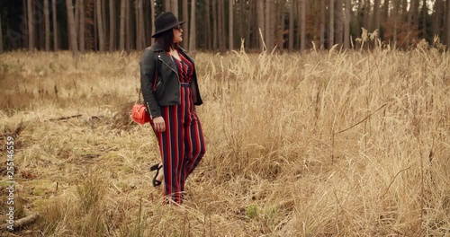 Young woman with hatwalking over a meadow inside a forest photo