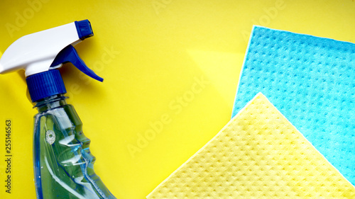 Housework, housekeeping and household concept - cleaning rag, detergent spray on yellow background