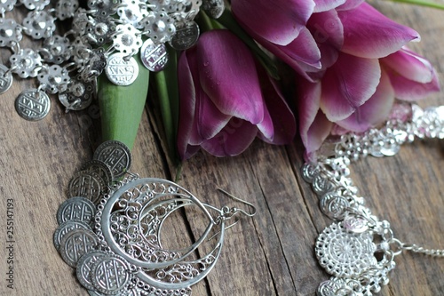 Indian decorations for dancing: earrings, necklace,  belt  for Punjabi folk dances and three purple tulips. Wooden background. photo