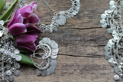 Indian decorations for dancing: earrings, necklace,  belt  for Punjabi folk dances and three purple tulips. Wooden background. photo