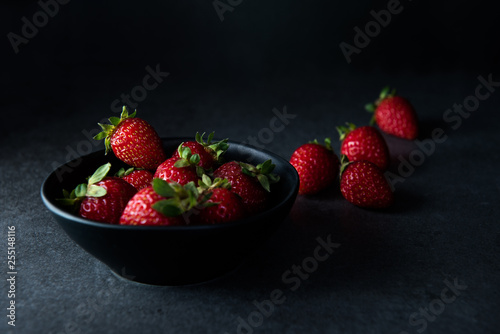 Strawberries in dark bowl with dark background  copy space  side view selective focus