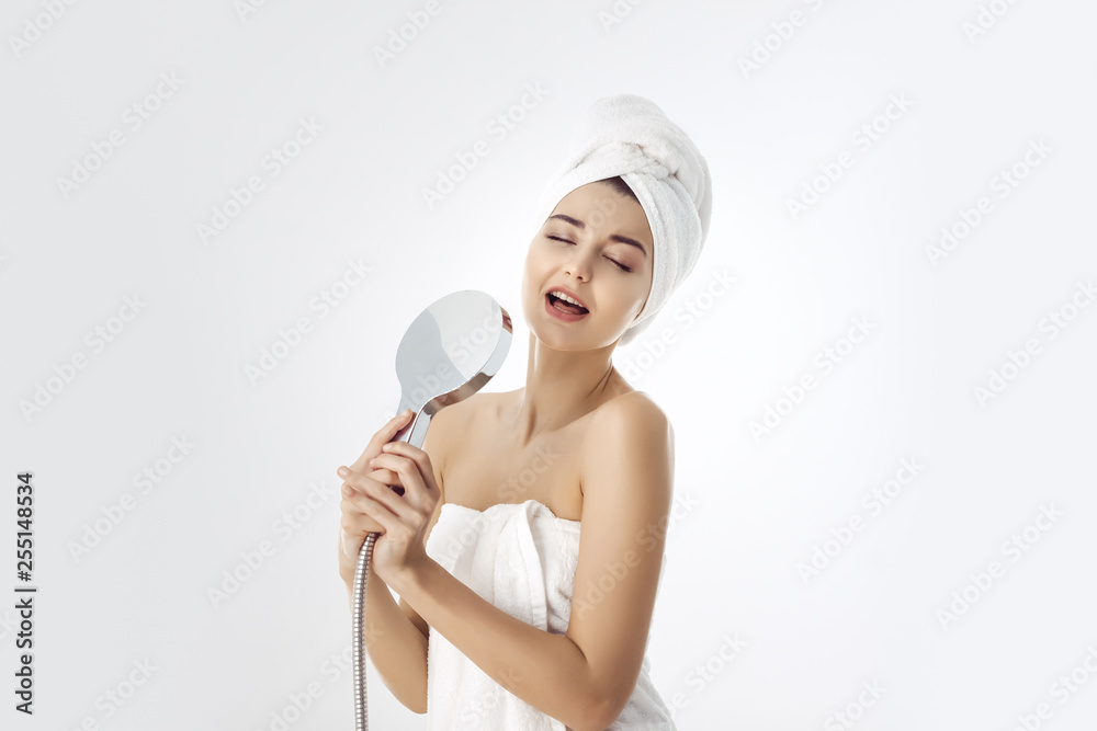 Young woman in a towel holding shower head Young woman in a towel holding shower head