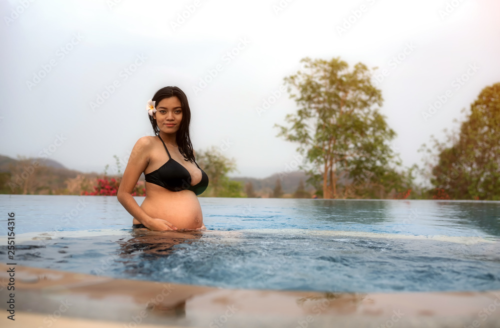 Fototapeta premium Asian pregnant woman with big belly. Relax and exercise and yoga at swimming pool, Water Yoga.