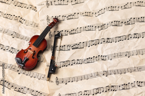 Miniature violin on old paper music notes with copy space