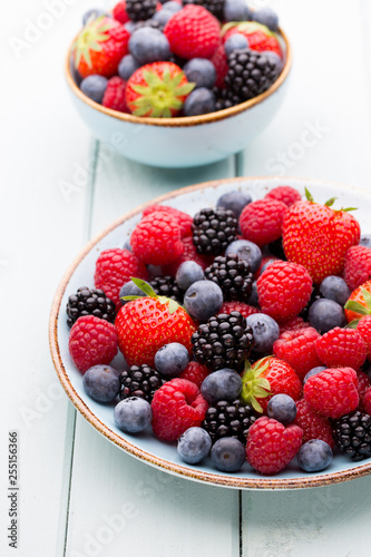 Fresh berry salad on blue dishes. Vintage wooden background.