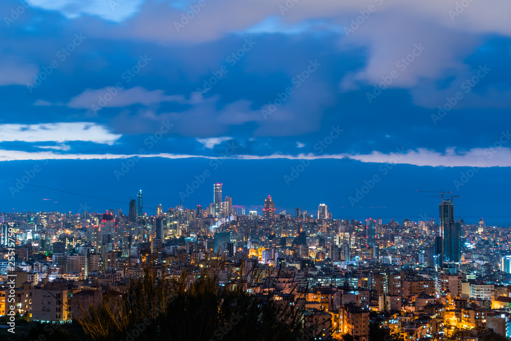 Naklejka premium To jest uchwycenie zachodu słońca w stolicy Libanu w Bejrucie z chłodnym niebieskim odcieniem, a na pierwszym planie widać centrum Bejrutu z piękną chmurą w tle