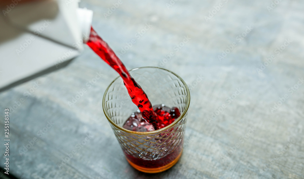 pour red drink fruit juice with alcohol in a glass
