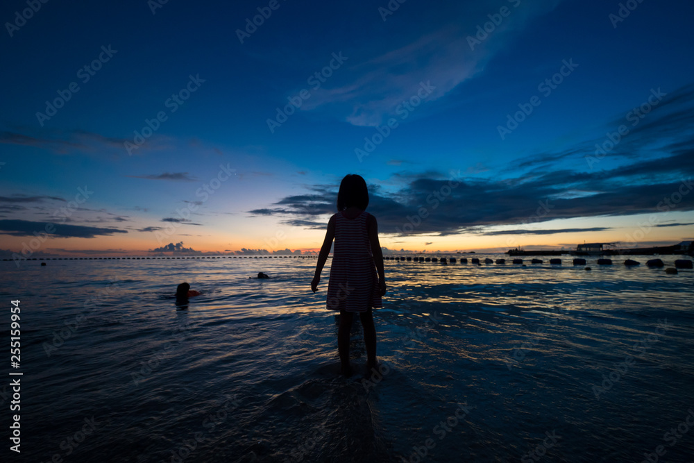 Fototapeta premium 綺麗な沖縄の夕焼けと砂浜で遊んでいる子供