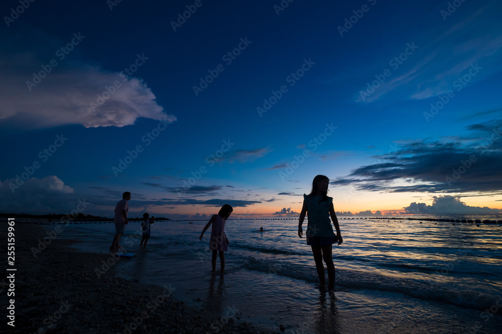 綺麗な沖縄の夕焼けと砂浜で遊んでいる子供