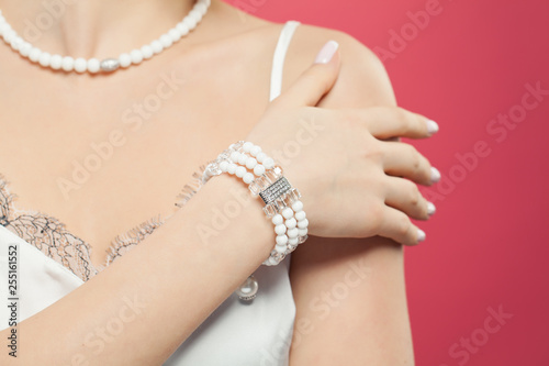 Woman hand wearing silver jewelry bracelet with pearls on pink background