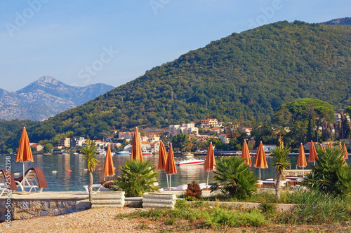 Summer beach vacation.  Beautiful Mediterranean landscape with beach umbrellas on sunny summer day. Montenegro, Adriatic Sea,  Bay of Kotor, Tivat photo