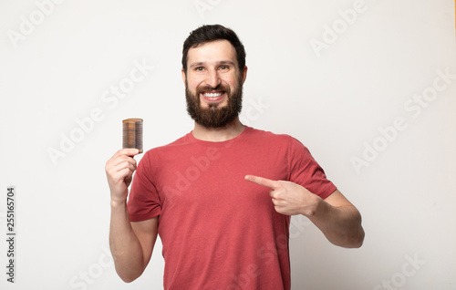 Attractive smiling Bearded man holding a comb for beard standing above grey background