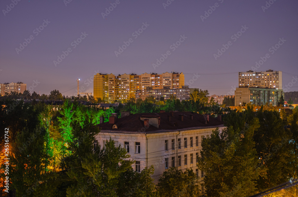 Night landscape. High-rise city houses with lights in the windows under the night sky